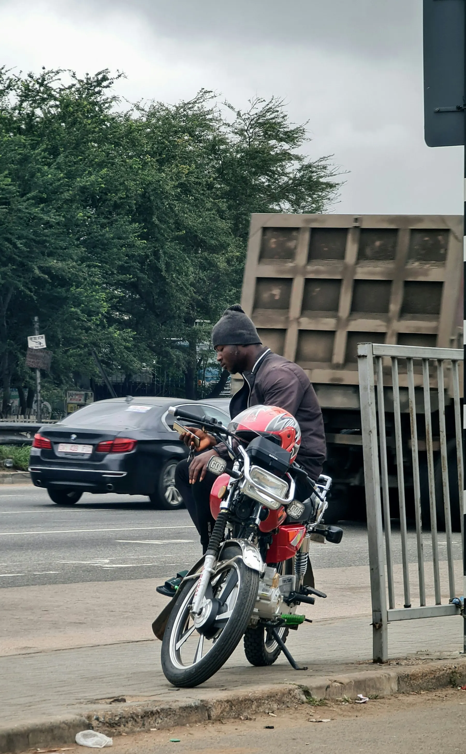 A dispatch rider with his motorbike at an Accra roadside